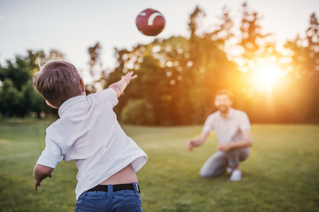 Young boy throwing football to father
